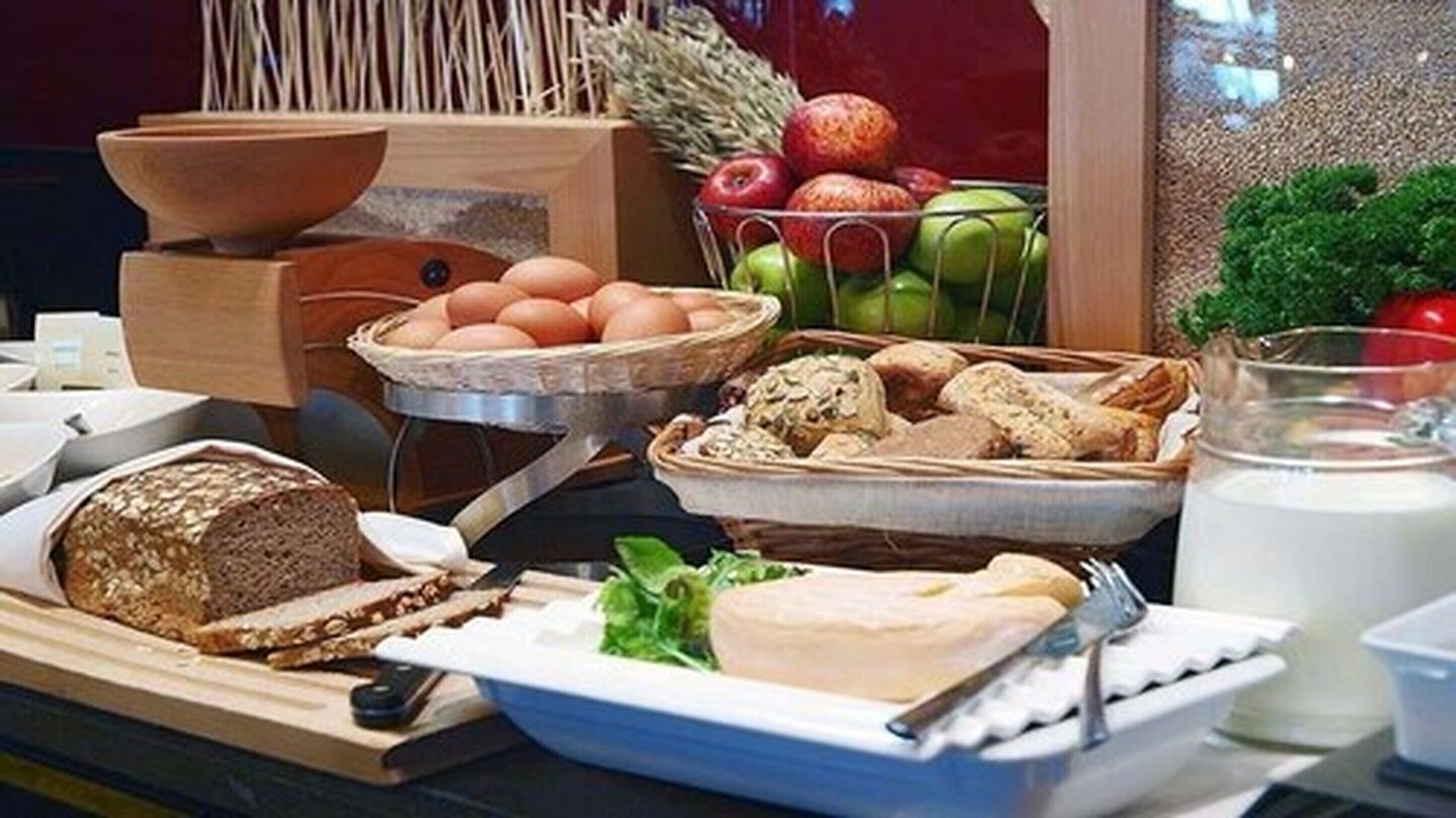 A breakfast buffet with bread, eggs, fruits, and milk.
