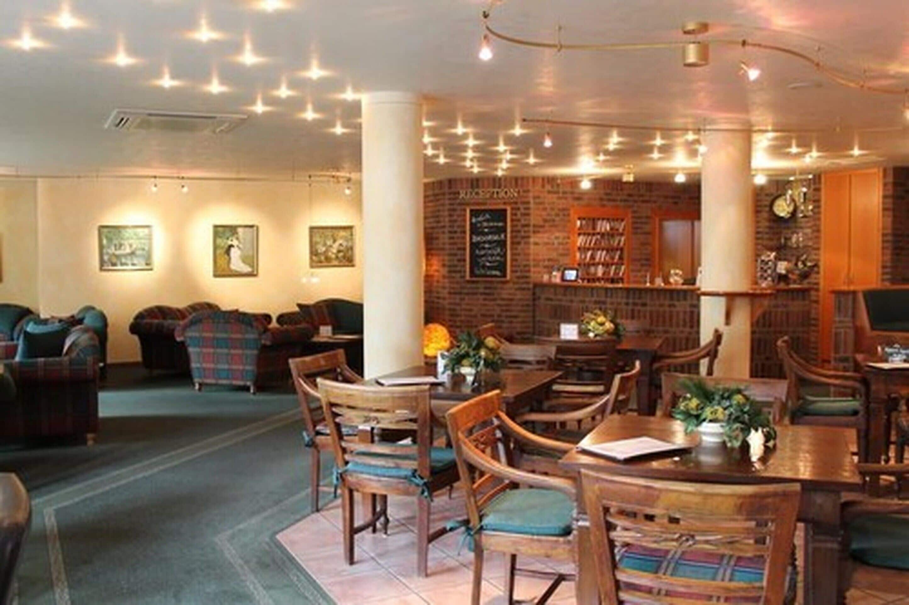 A cozy restaurant with wooden furniture, a brick wall, and string lights.