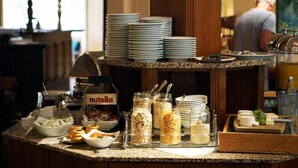 Un buffet avec des assiettes, des bols et des récipients remplis de nourriture, et une pancarte bien visible indiquant la présence de Nutella.