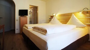 Une chambre d’hôtel comprenant un lit, un téléviseur, une tête de lit en bois et un espace douche.