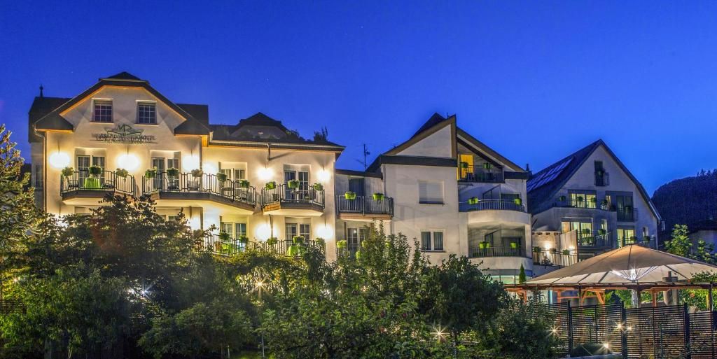 Un hotel de varios pisos con balcones, un espacio al aire libre cubierto y montañas al fondo.