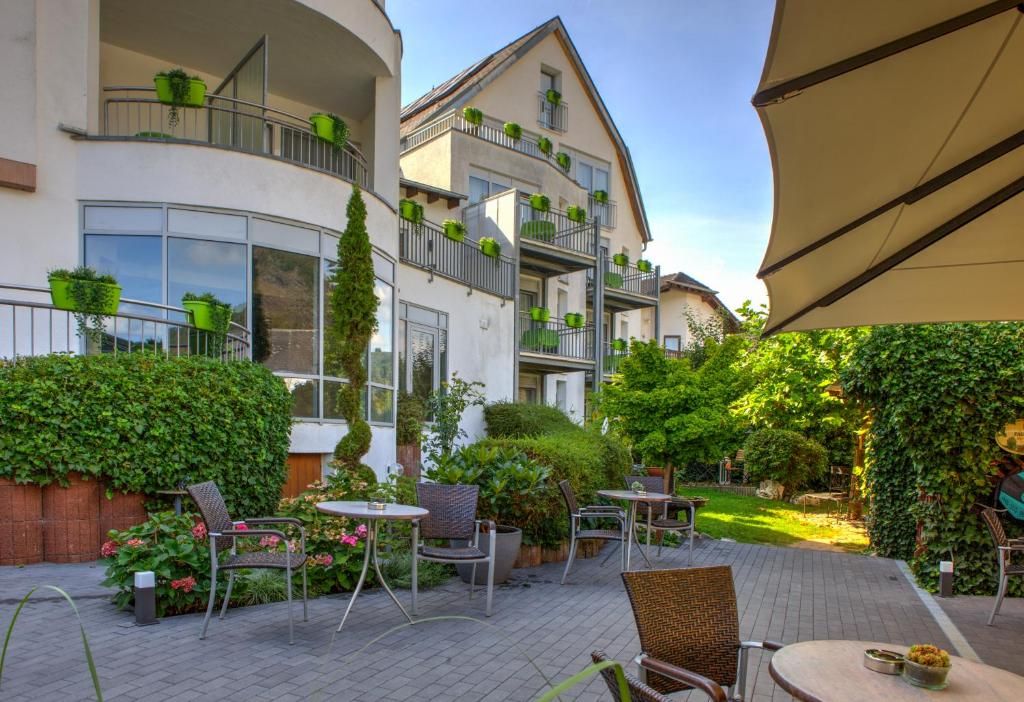 Un patio con mesas al aire libre, un edificio con balcones y una sombrilla grande.