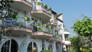 Un hôtel doté de nombreux balcons agrémentés de jardinières verdoyantes, d’un salon central et d’un espace de détente extérieur.