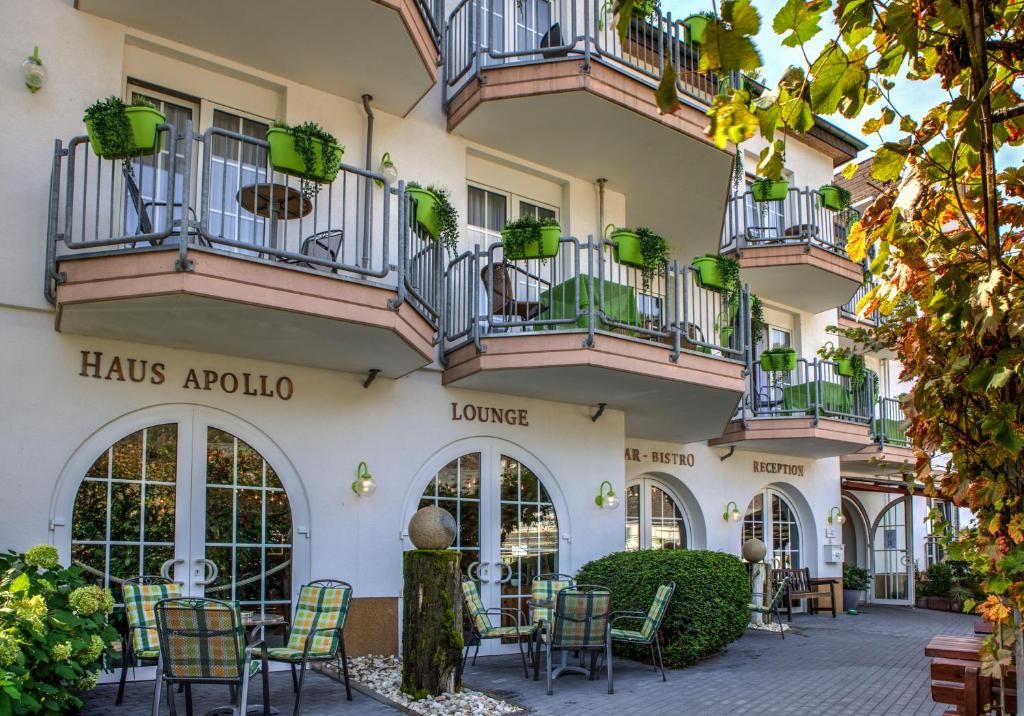 A hotel with outdoor seating, multiple balconies with plants, and a reception area.