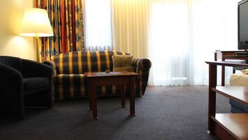 Een hotelkamer met een bank, een kleine tafel, een lamp en een televisie.