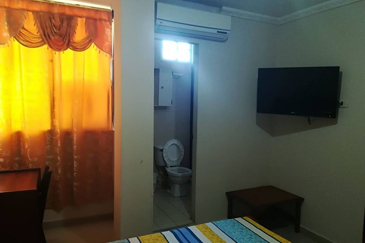 Une chambre d’hôtel équipée d’un lit, d’un téléviseur fixé au mur, d’une petite table et d’un appareil de climatisation.