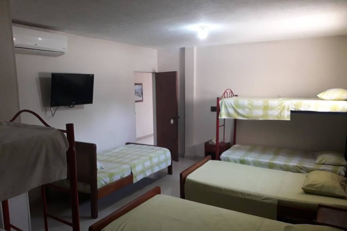 Une chambre de dortoir équipée de lits superposés, d’un téléviseur et d’un appareil de climatisation.