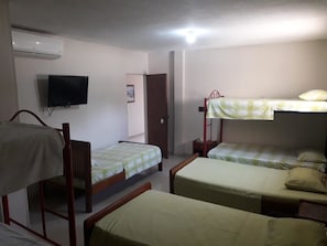 A dormitory room with bunk beds, a television, and an air conditioning unit. - Hotel Granada Inn (Barranquilla)