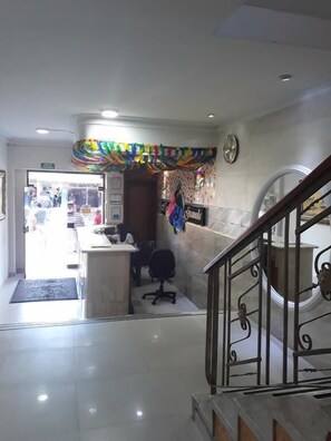 A reception area with a counter, office chairs, and a decorative wall. - Hotel Granada Inn (Barranquilla)