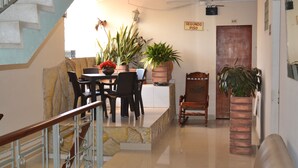 A dining area with a table, chairs, potted plants, and a staircase. - Hotel Granada Inn (Barranquilla)