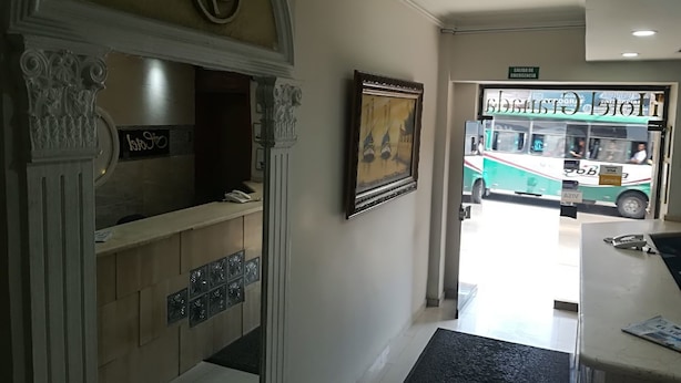 A reception area with a reception desk, framed artwork, and a sign indicating an emergency exit. - Hotel Granada Inn (Barranquilla)