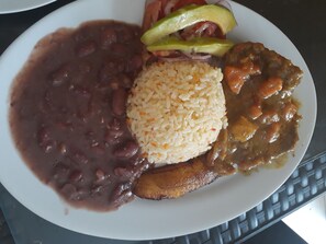 A plate with beans, rice, meat, and vegetables. - Hotel Granada Inn (Barranquilla)