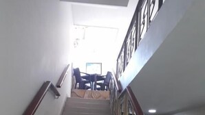 A staircase with a wooden handrail and metal balusters, leading to a room with a bed and a window. - Hotel Granada Inn (Barranquilla)