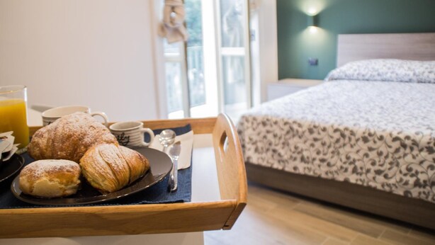 A breakfast tray with pastries and a glass of orange juice on a wooden tray in a hotel room. - Interno 10 Cavour (Naples)