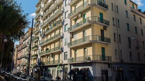 A multi-story building with balconies, parked cars, and pedestrians. - Interno 10 Cavour (Naples)