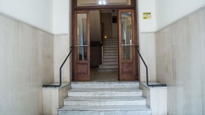 A set of marble stairs leading to a wooden door with glass panels and metal handrails. - Interno 10 Cavour (Naples)