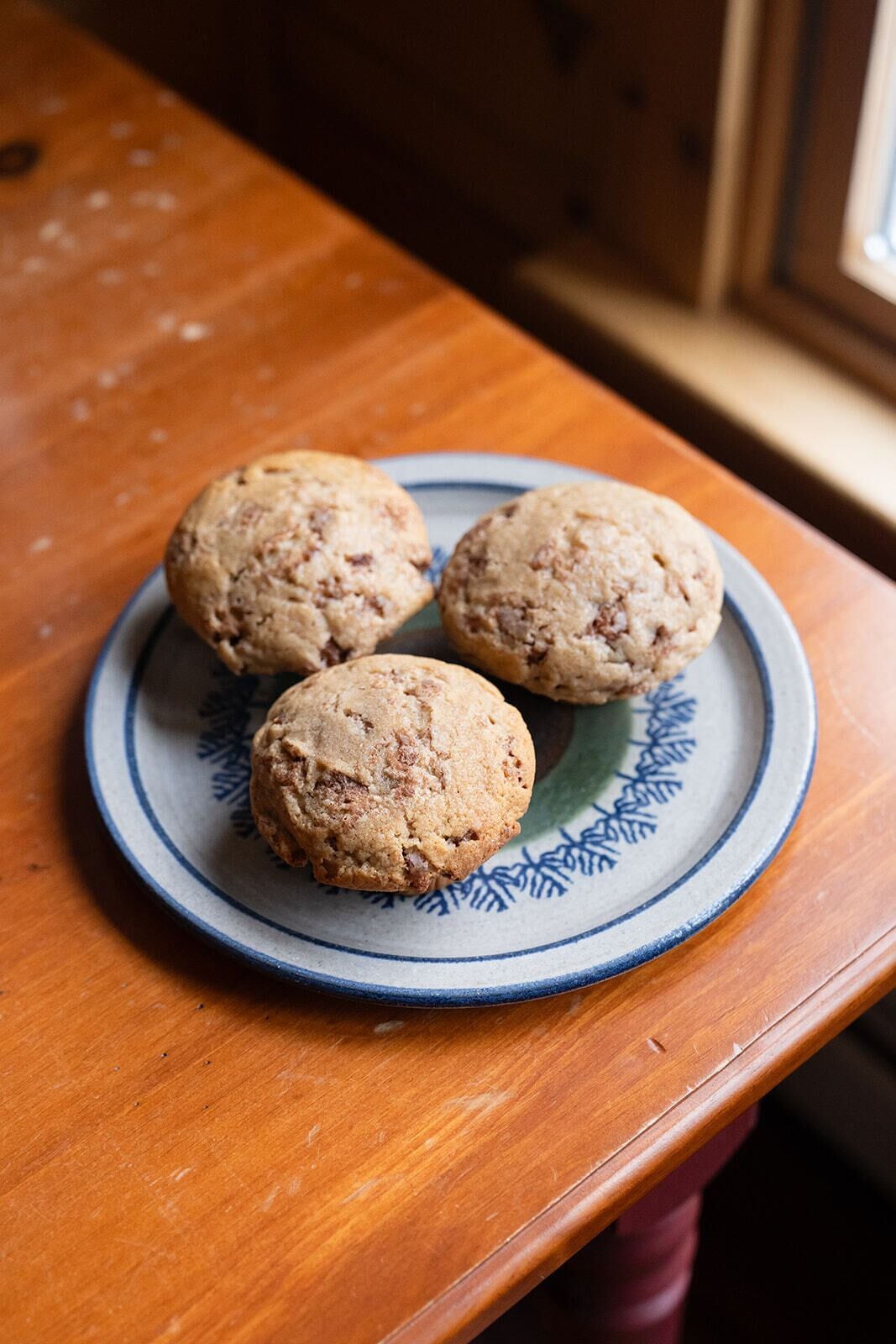 Tres galletas sobre un plato azul y blanco sobre una mesa de madera.