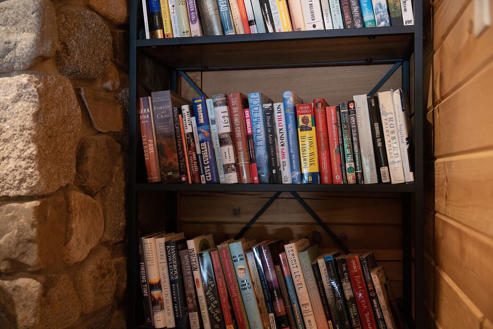 Una estantería llena de libros frente a una pared de piedra.