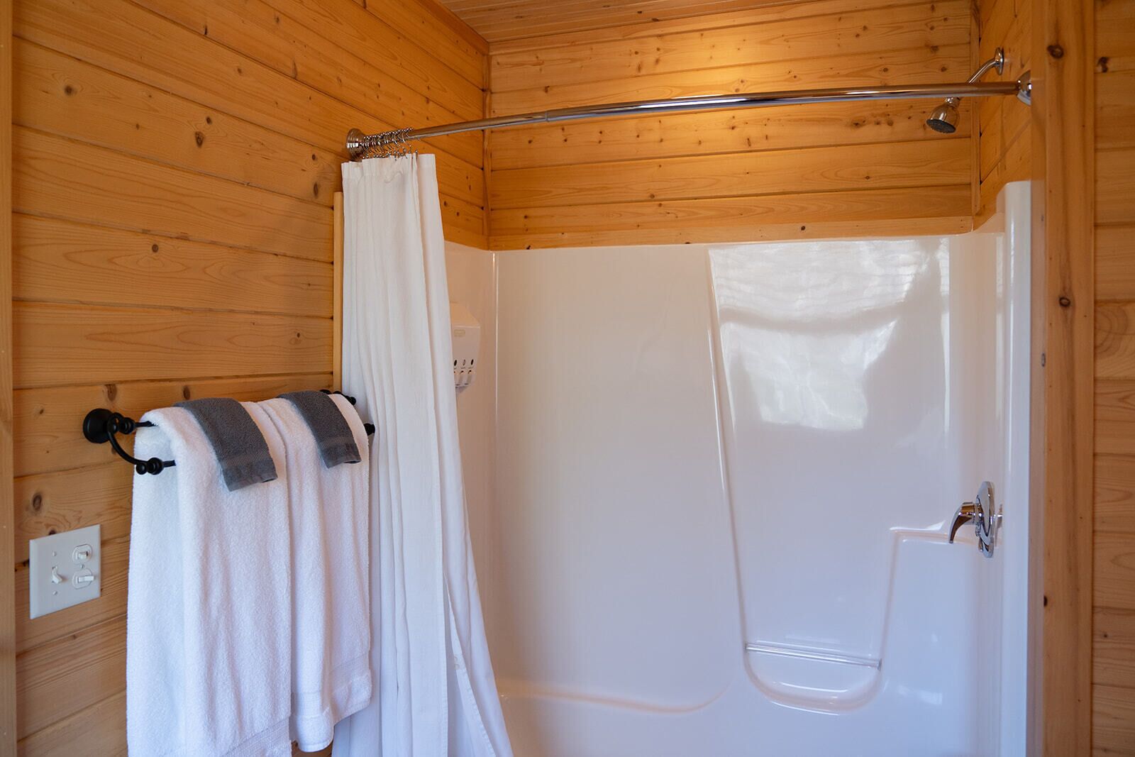 A wooden-paneled bathroom with a shower and a towel rack with a towel.