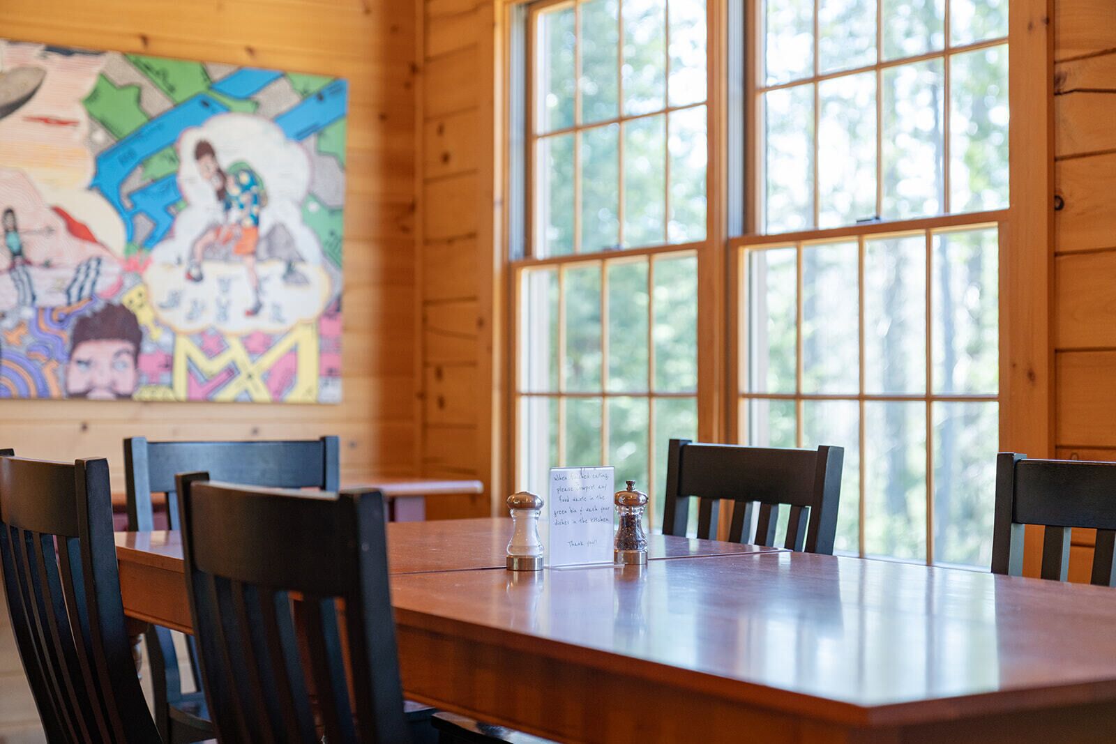 Una mesa de comedor de madera con sillas, un salero y pimentero, y un letrero de menú.