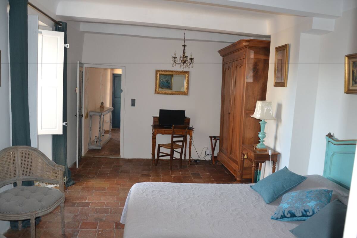 Ein Schlafzimmer mit Bett, Schreibtisch, Stuhl, Kleiderschrank und einer Chandelier.