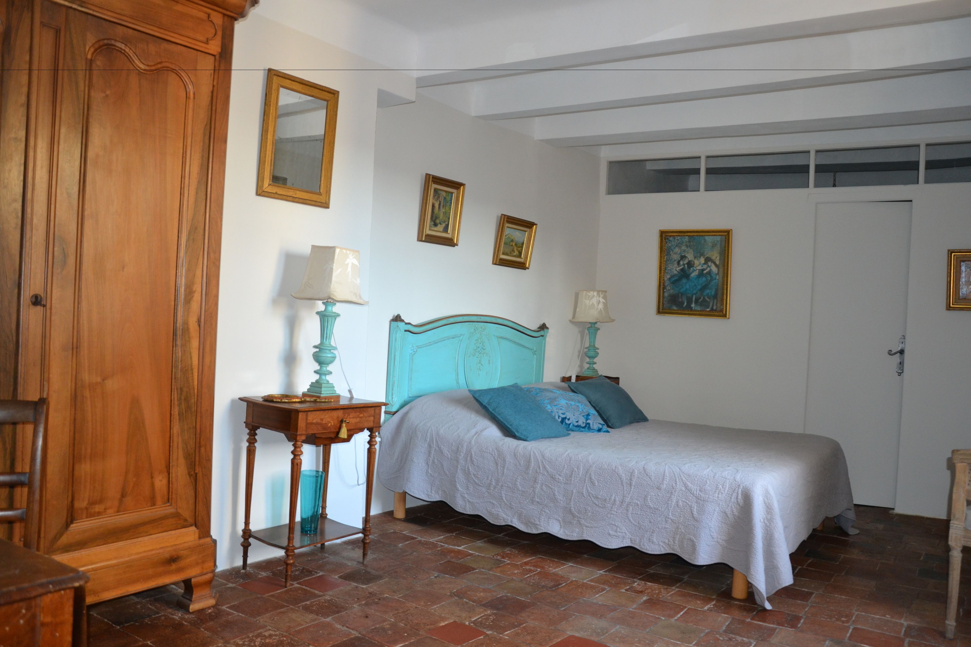 Une chambre à coucher avec un lit, une armoire en bois et un sol carrelé.