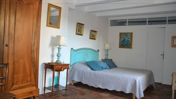 Une chambre à coucher avec un lit, une armoire en bois et un sol carrelé.