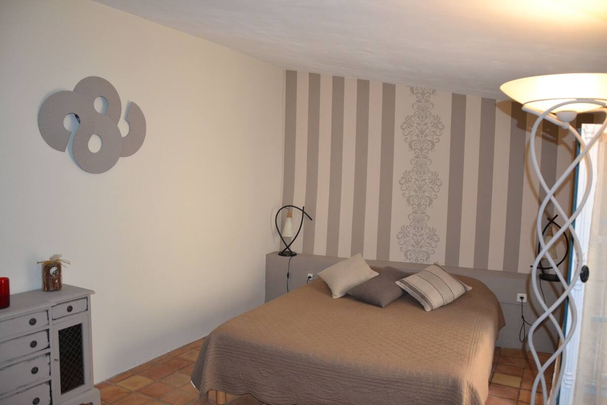 Ein Schlafzimmer mit Bett, Schminktisch, Lampe und einer Wand mit Streifenmuster.
