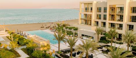 Un resort con piscina, palmeras y vista al mar.