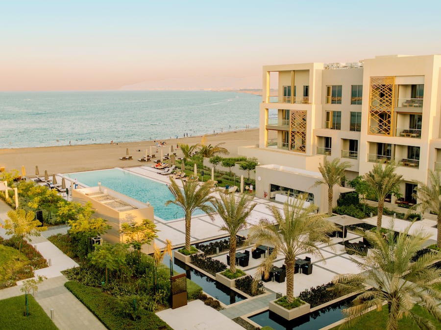 A resort with a pool, palm trees, and a beach view.