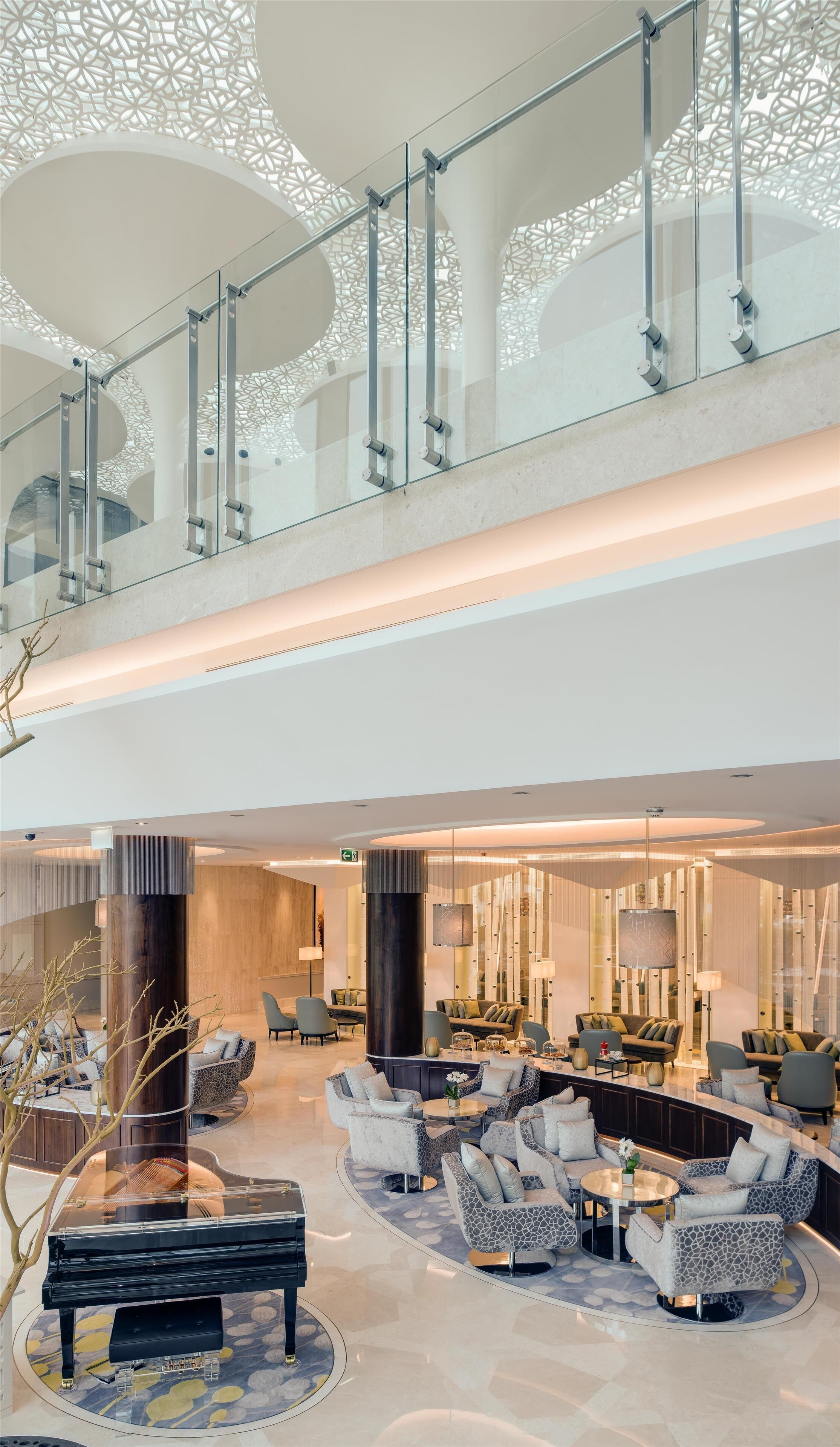 A spacious lobby with a high ceiling, a glass railing, and a modern design.