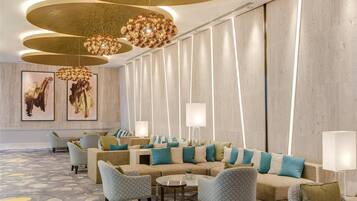 Un moderno vestíbulo de hotel con una larga recepción, asientos cómodos e iluminación de techo original.