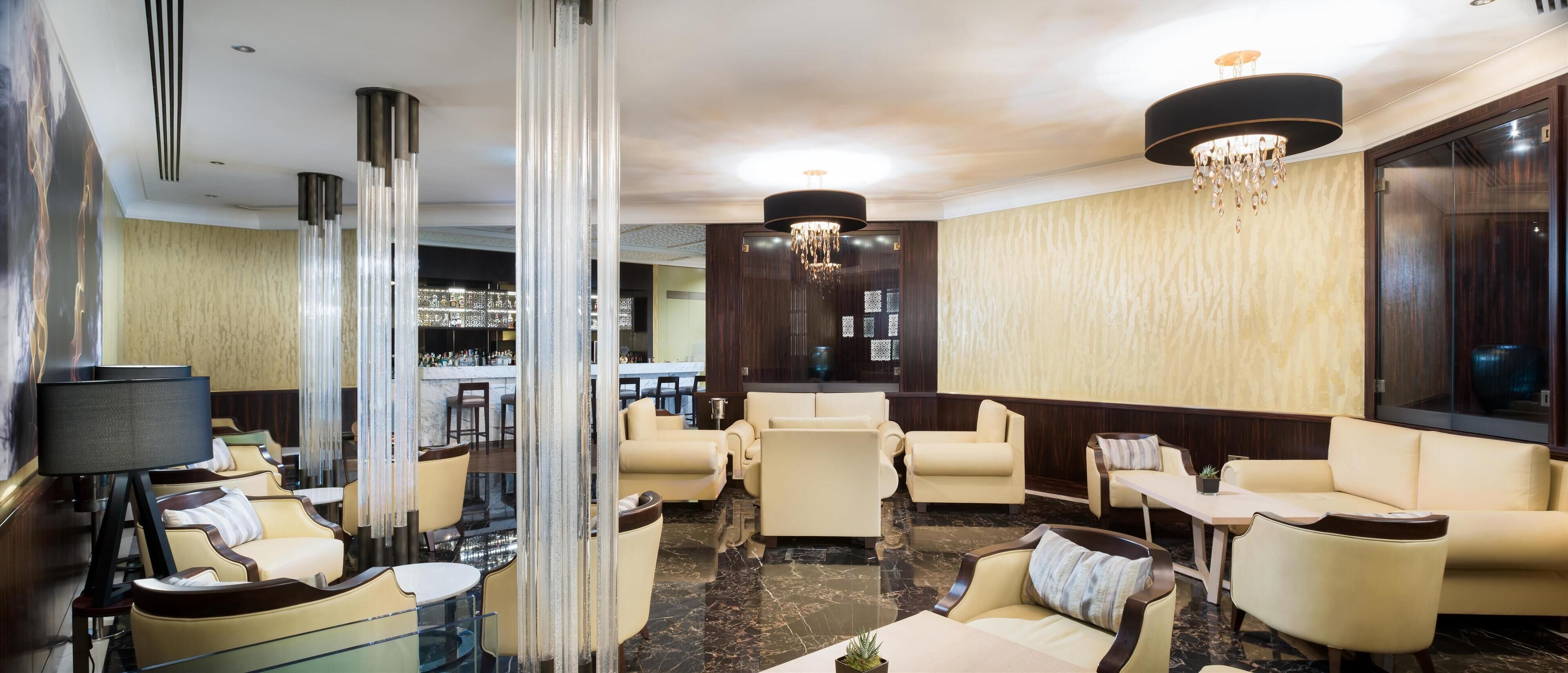 A modern lounge area with leather sofas, a bar, and a chandelier.