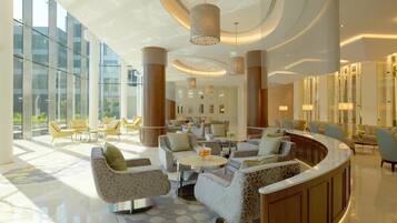 A spacious lobby with modern furniture, large windows, and a curved reception desk.