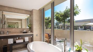 A modern bathroom with a large bathtub, a vanity with a mirror, and a view of the outdoor area.