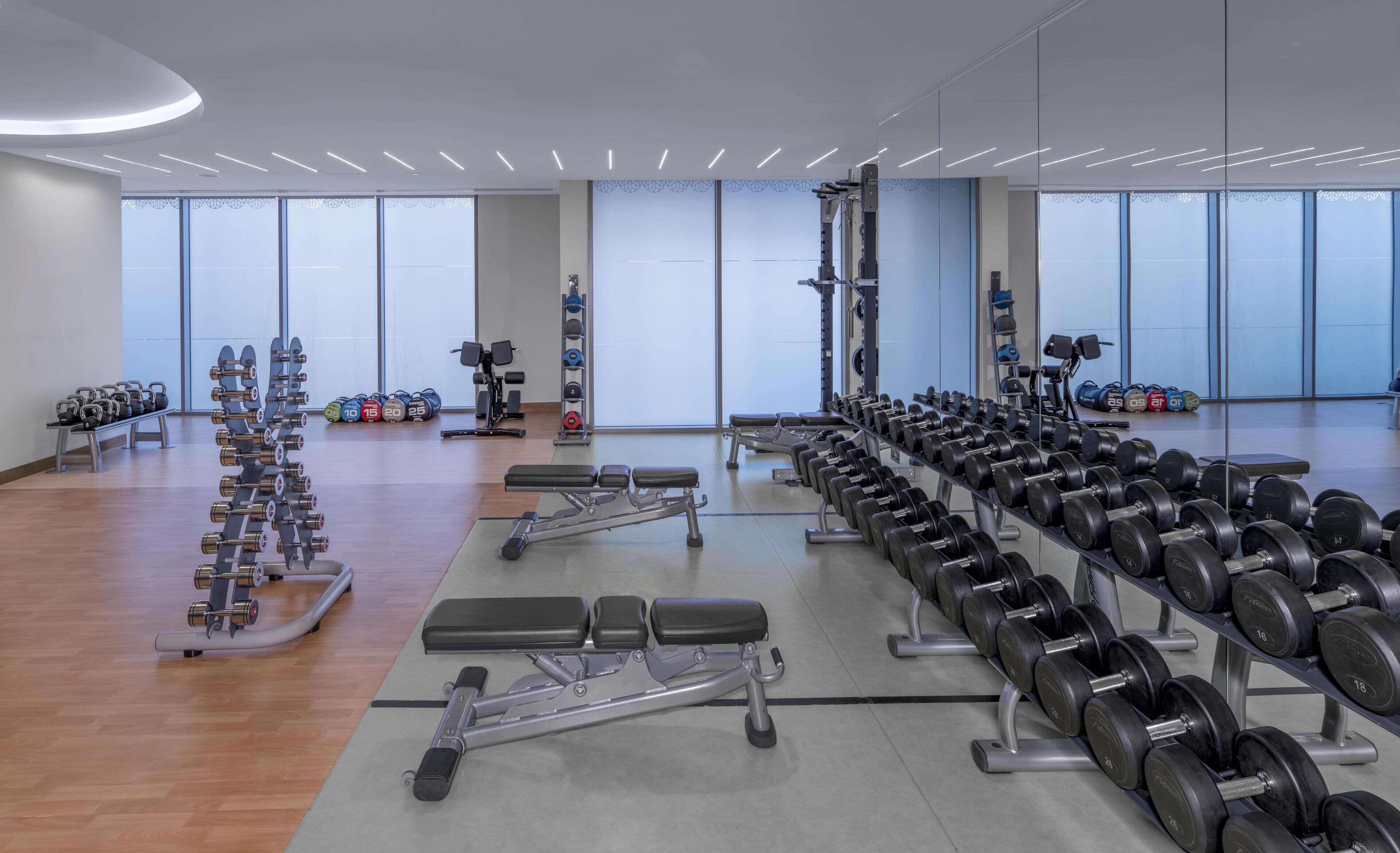 A gym with weightlifting equipment, benches, and dumbbells.