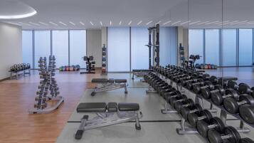 A gym with weightlifting equipment, benches, and dumbbells.