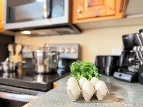 A kitchen counter with a carton of eggs, a pot, and a green vegetable.