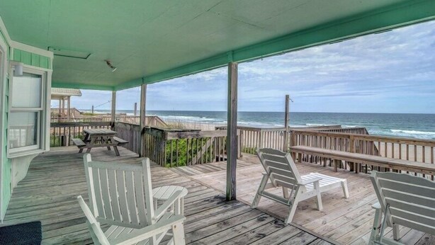 A covered porch with wooden chairs and a table, overlooking the ocean. - Bright's Beach Front | Sound View + Walk to Beach! (Topsail Beach)