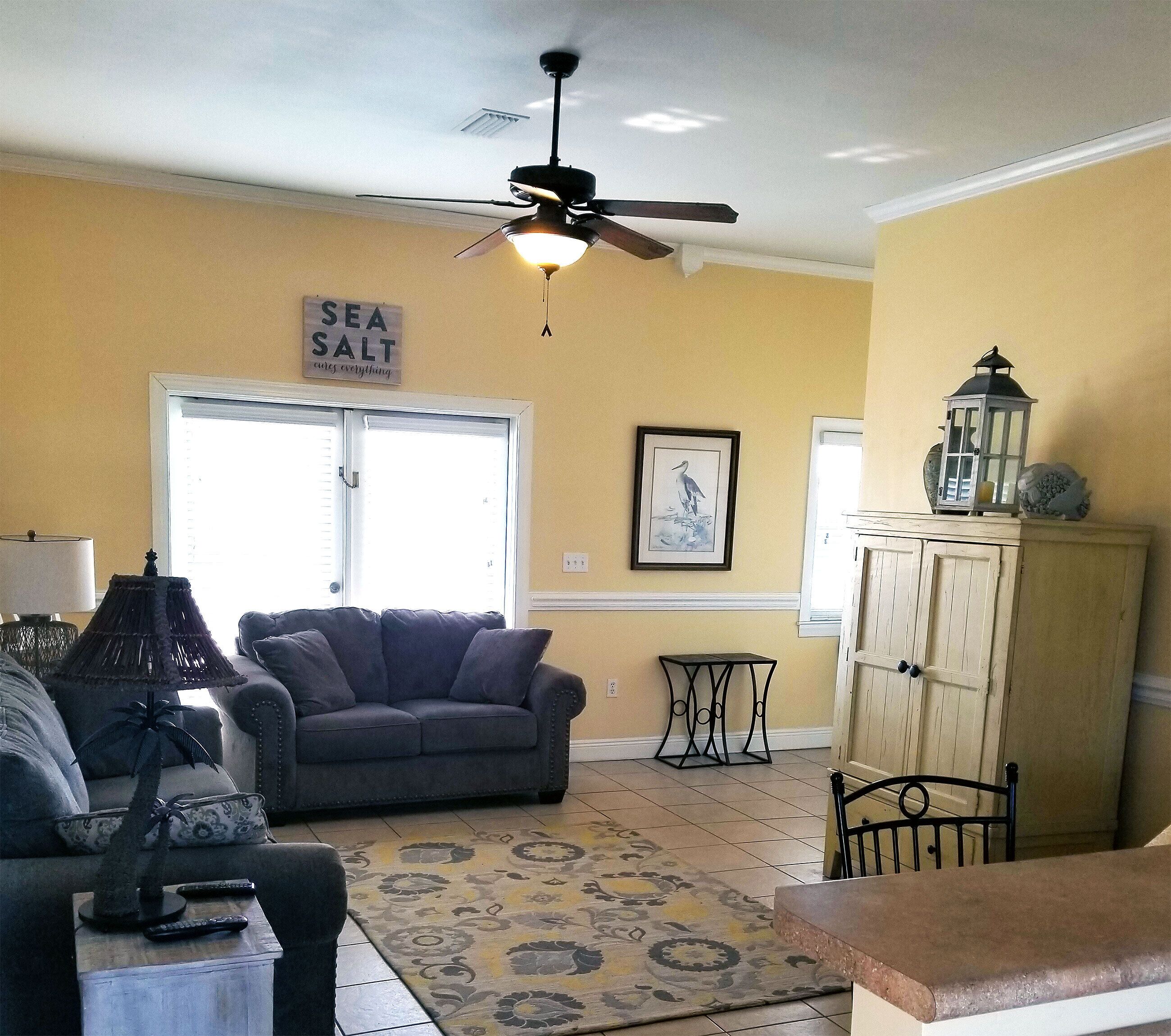 A living room with a ceiling fan, a sofa, a small table, and a cabinet.