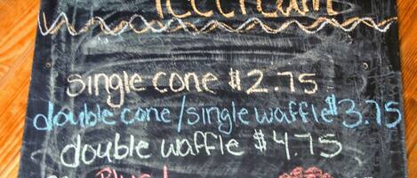 A chalkboard menu listing prices for Blue Bell ice cream cones and waffles.