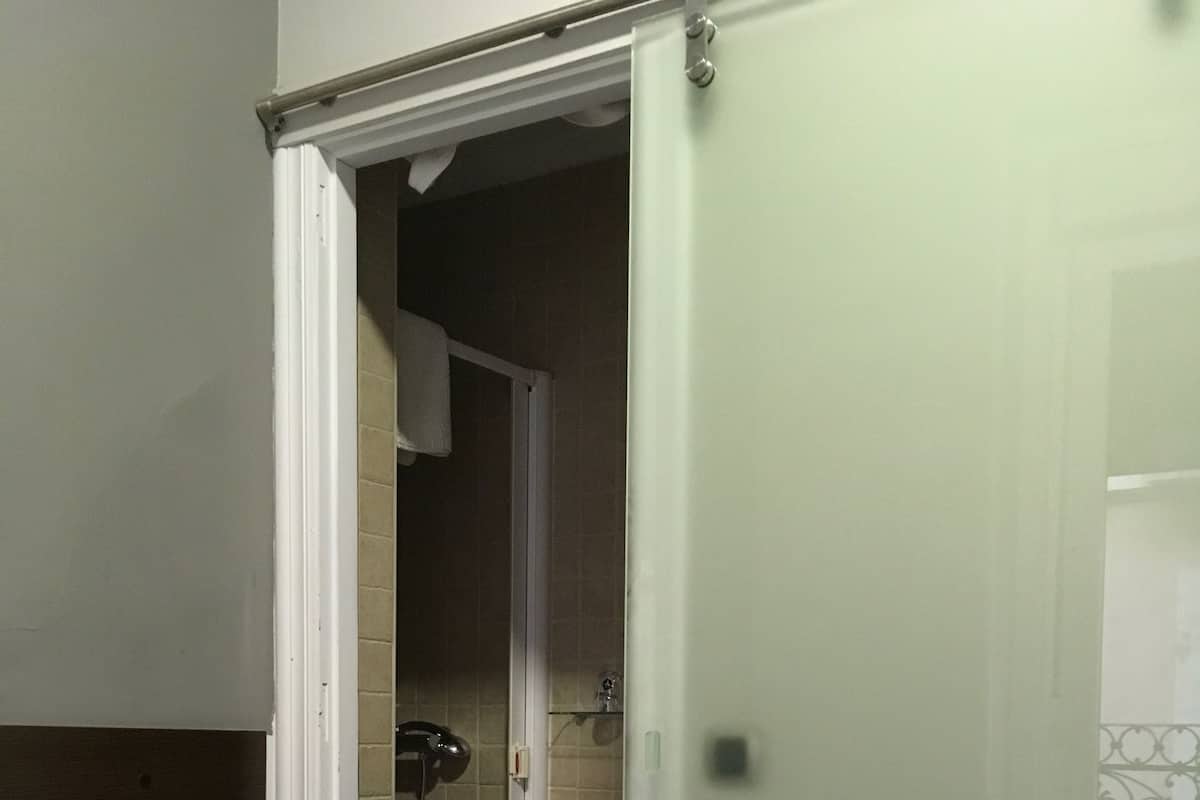 A room with a bed, a sliding door leading to a bathroom, and a tiled floor.