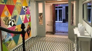 A hallway with a colorful geometric mural, a patterned tiled floor, and a staircase leading to another room. - Pensión La Bilbaina - Albergue Logroño (Logroño)