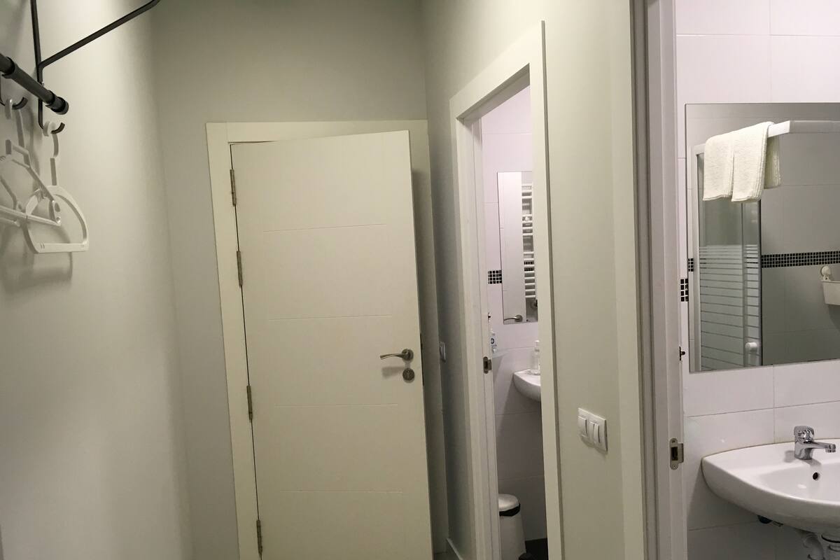 A narrow hallway leading to a bathroom with a white sink and mirror.