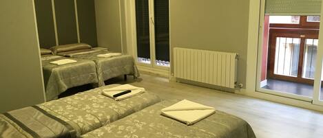 A room with two beds, a radiator, and a view of the outside.