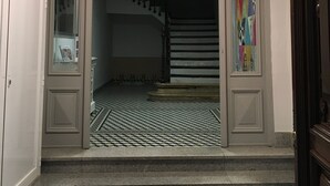 A staircase with a checkered floor leading to a landing with a glass door and a wall with a geometric pattern. - Pensión La Bilbaina - Albergue Logroño (Logroño)