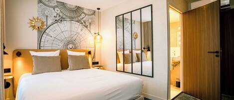 A hotel room with a large bed, a wall map, a mirror, and a wooden door.