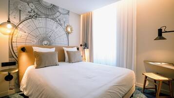 Una habitación de hotel con una cama grande, un escritorio, una silla y un globo terráqueo en la pared.