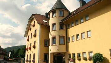 Ein gelbes Gebäude mit einem Turm, zahlreichen Fenstern und Blumenkästen.