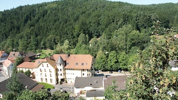 A building with a tower, surrounded by trees and a hill.